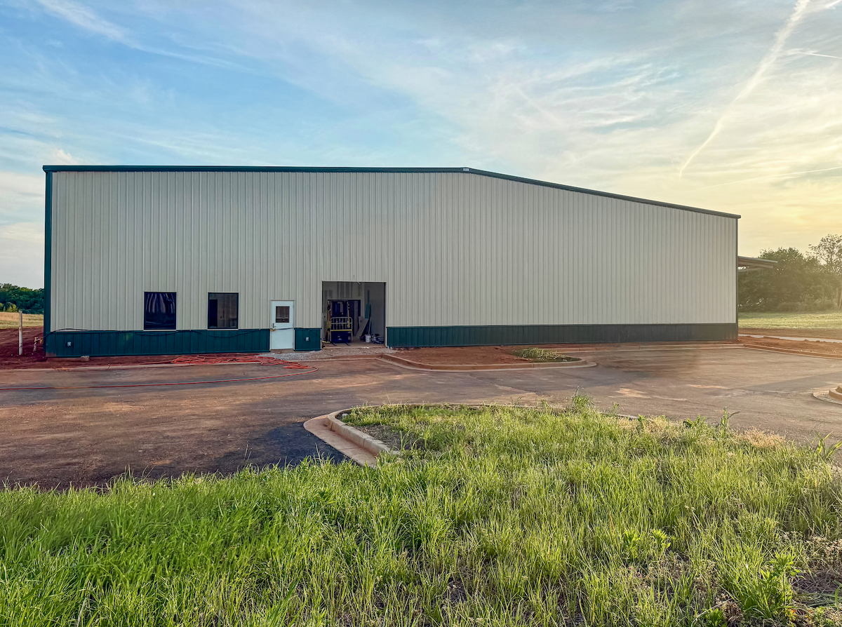Outside view of Frontier Meat Packing facility. Tan and Green metal building with windows and doors. 